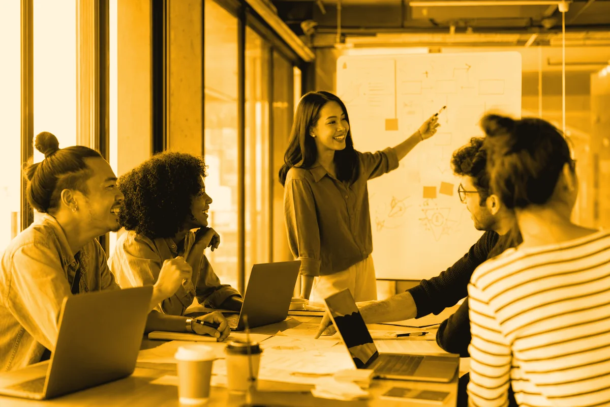 A team huddled around a whiteboard mid-discussion during a training sprint